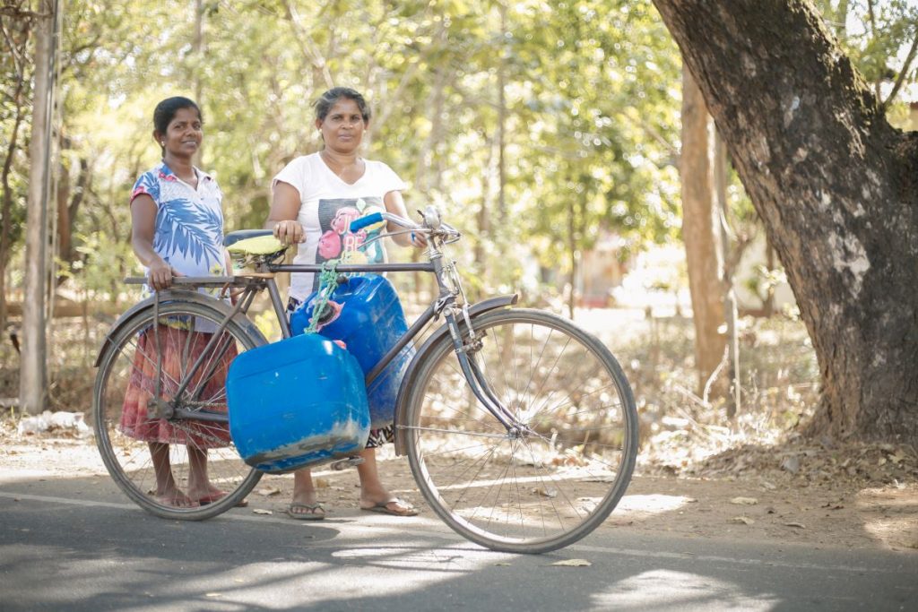 village women carrying water bottles